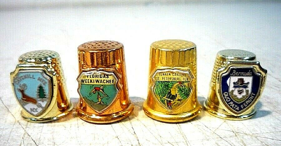 Four vintage metal plastic thimbles with designs of places and destinations.
