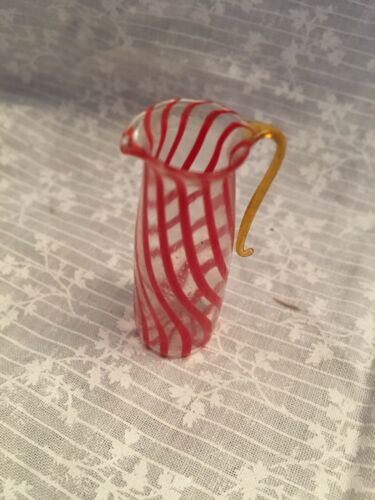 miniature glass pitcher. Red stripes with an amber handle.  2 inches