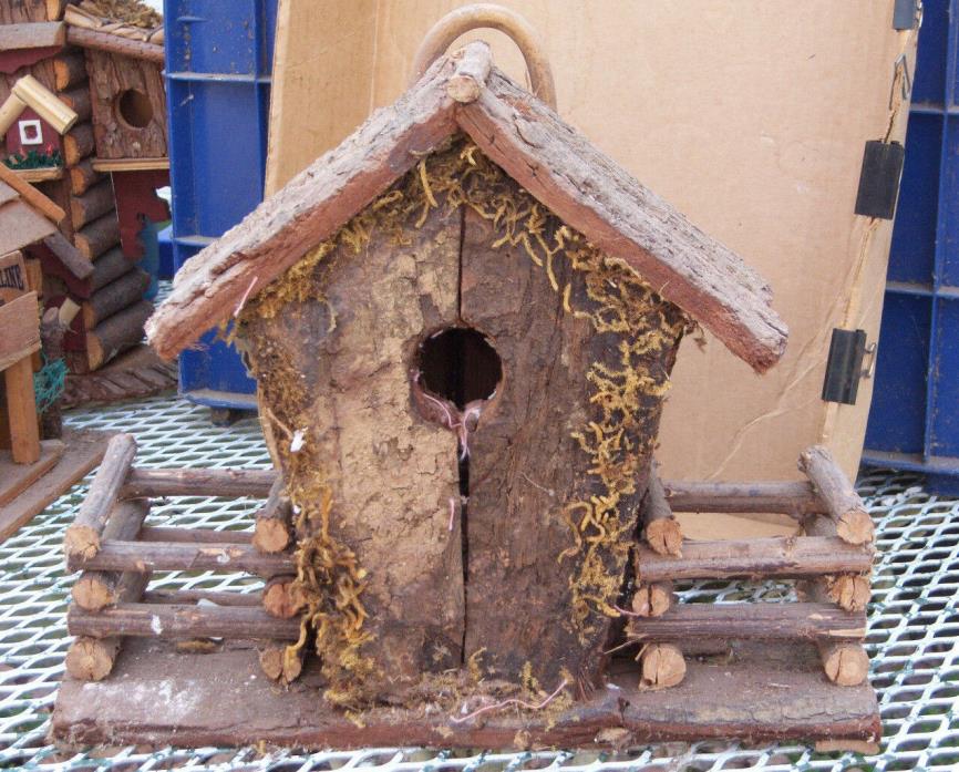 Wooden bird  house decorated with straw and a carral on each side