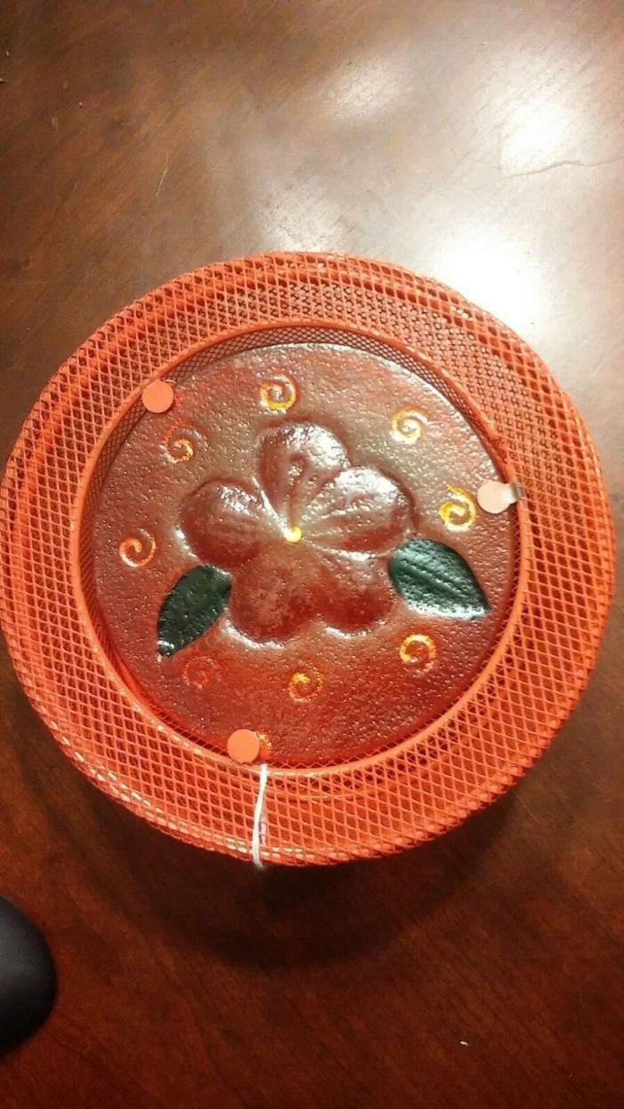 Open mesh round orange basket with glass insert with flower.